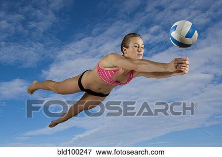 Stock Photo - Caucasian volleyball player hitting volleyball. Fotosearch