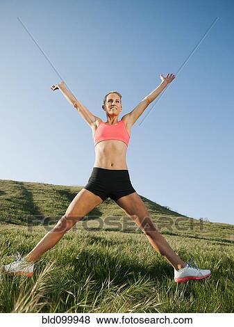 Stock Photo - Caucasian woman in sportswear jumping in the air. Fotosearch