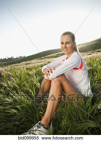 Stock Photography - Caucasian woman in sportswear sitting in field. Fotosearch