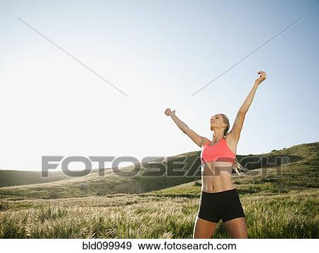 Stock Photo - Caucasian woman in sportswear with arms raised. Fotosearch