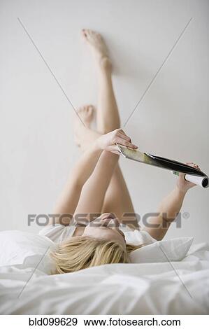 Caucasian woman laying in bed reading magazine View Large Photo Image Stock Photo - Caucasian woman laying in bed reading magazine. Fotosearch