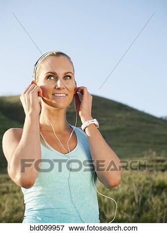 Stock Photo - Caucasian woman listening to mp3 player before exercise. Fotosearch