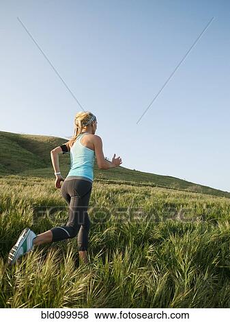 Stock Photo - Caucasian woman running in remote field. Fotosearch