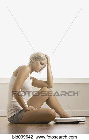 Caucasian woman sitting on floor near scale View Large Photo Image Stock Image - Caucasian woman sitting on floor near scale. Fotosearch