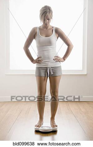 Caucasian woman standing on scale View Large Photo Image Stock Photo - Caucasian woman standing on scale. Fotosearch