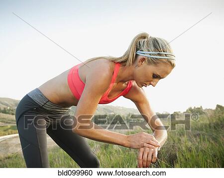Stock Image - Caucasian woman taking her pulse after exercise. Fotosearch