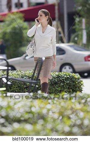 Stock Photo - Caucasian woman using, cell phone outdoors. Fotosearch