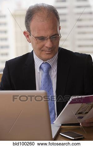 Chilean businessman looking at paperwork at desk View Large Photo Image Stock Image - Chilean businessman looking at paperwork at desk. Fotosearch