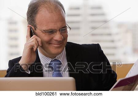 Stock Image - Chilean businessman talking on cell phone at desk. Fotosearch
