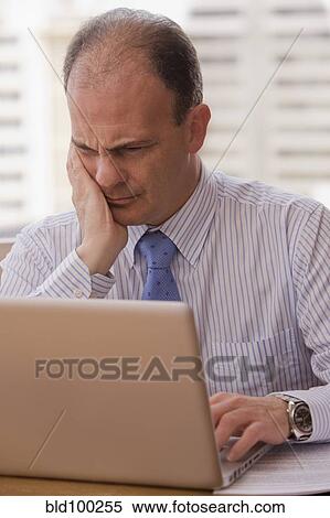 Stock Photography - Chilean businessman using laptop at desk. Fotosearch