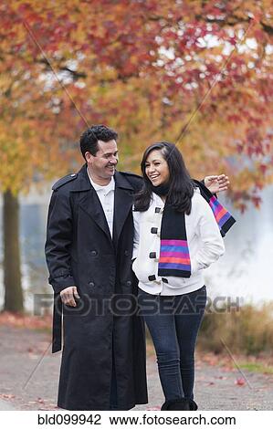 Stock Image - Hispanic father and daughter walking in park. Fotosearch