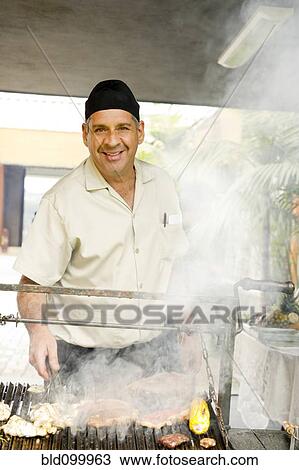 Hispanic man cooking food on barbecue grill View Large Photo Image Stock Image - Hispanic man cooking food on barbecue grill. Fotosearch