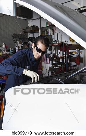 Stock Photo - Hispanic mechanic working on car. Fotosearch