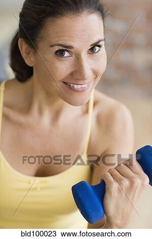 Stock Image - Hispanic woman exercising with dumbbells. Fotosearch
