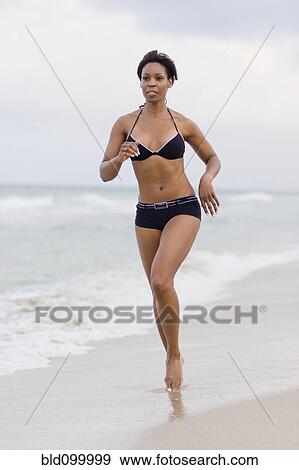 Stock Photo - Jamaican woman in bikini running on beach. Fotosearch