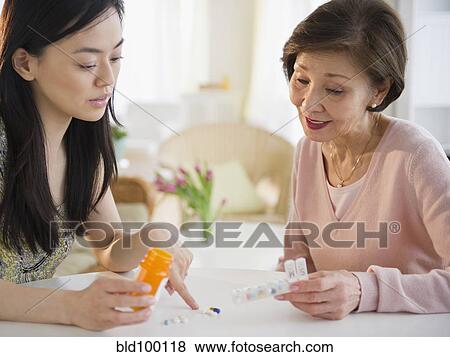 Stock Photo - Japanese daughter explaining, medication to mother. Fotosearch