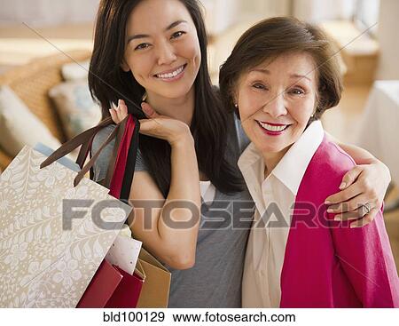 Stock Photo - Japanese daughter holding shopping bags and hugging mother. Fotosearch