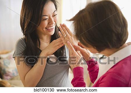 Stock Image - Japanese daughter showing engagement ring to mother. Fotosearch