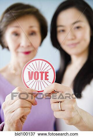 Stock Photo - Japanese mother and daughter holding vote sticker. Fotosearch