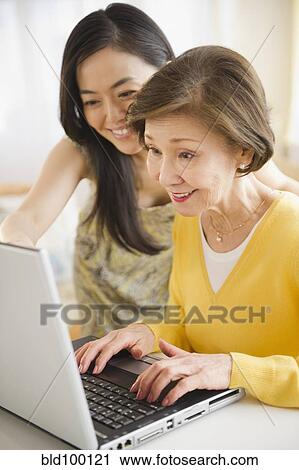 Stock Image - Japanese mother and daughter using laptop together. Fotosearch