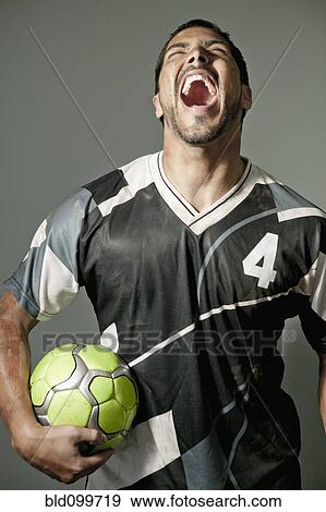 Stock Photo - Laughing athlete holding soccer ball. Fotosearch