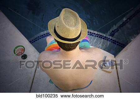 Stock Photography - Man sitting at poolside. Fotosearch