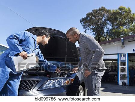 Mechanic talking to customer about car engine View Large Photo Image Stock Photograph - Mechanic talking to customer about car engine. Fotosearch