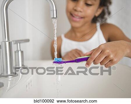 Stock Image - Mixed race girl brushing her teeth. Fotosearch