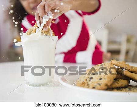 Mixed race girl dunking cookie into milk View Large Photo Image Stock Image - Mixed race girl dunking cookie into milk. Fotosearch