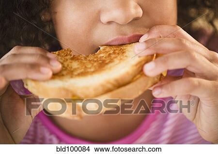 Picture - Mixed race girl eating sandwich. Fotosearch