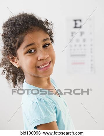 Stock Image - Mixed race girl having an eye exam. Fotosearch