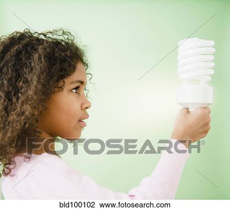 Stock Image - Mixed race girl holding CFL lightbulb. Fotosearch