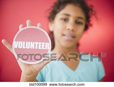 Stock Photo - Mixed race girl holding volunteer sticker. Fotosearch