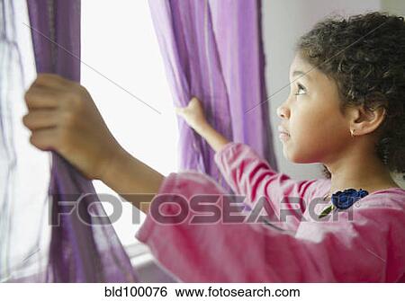 Stock Photograph - Mixed race girl opening curtains. Fotosearch