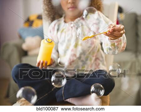 Stock Photo - Mixed race girl playing with bubbles. Fotosearch