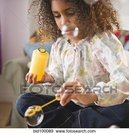 Stock Photo - Mixed race girl playing with bubbles. Fotosearch
