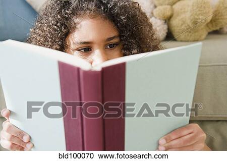 Stock Image - Mixed race girl reading book. Fotosearch