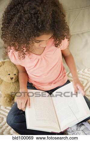Stock Photo - Mixed race girl reading book. Fotosearch