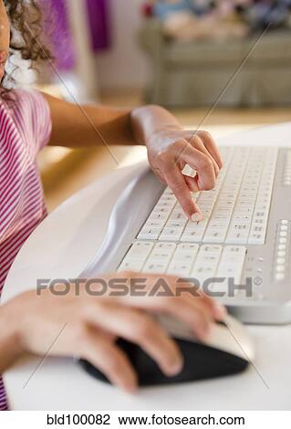 Stock Image - Mixed race girl using computer keyboard. Fotosearch