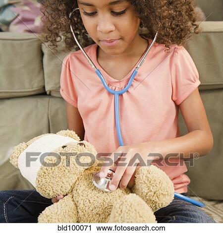 Stock Image - Mixed race girl using stethoscope on teddy bear. Fotosearch