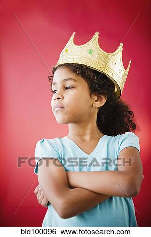Stock Photograph - Mixed race girl with arms crossed wearing crown. Fotosearch