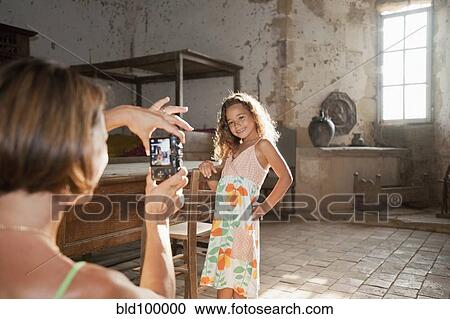 Stock Image - Mother taking photograph of daughter. Fotosearch
