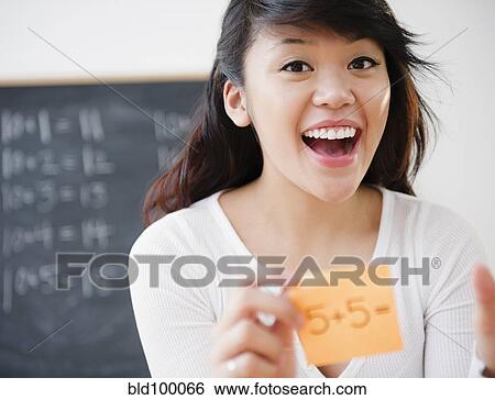Stock Photograph - Pacific Islander teacher holding sticky note with math problem. Fotosearch