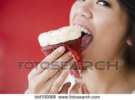 Stock Photo - Pacific Islander woman eating cupcake. Fotosearch