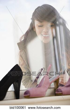 Stock Image - Pacific Islander woman looking at high heels in store. Fotosearch