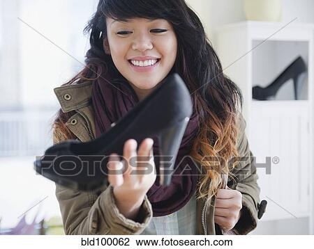 Stock Image - Pacific Islander woman looking at high heels in store. Fotosearch