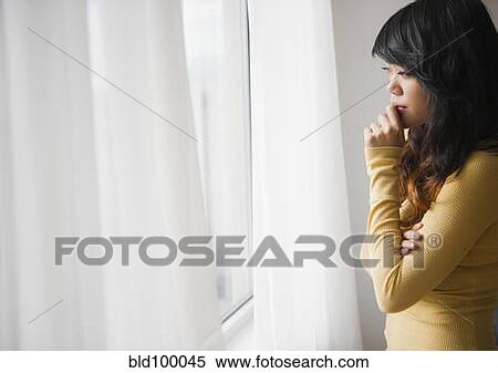Stock Photography - Pacific Islander woman looking out window. Fotosearch