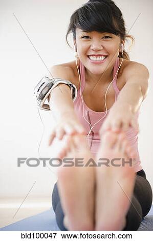 Stock Photo - Pacific Islander woman stretching before exercise. Fotosearch