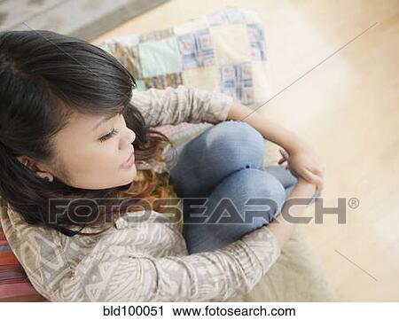 Stock Image - Pacific Islander woman thinking and sitting on sofa. Fotosearch