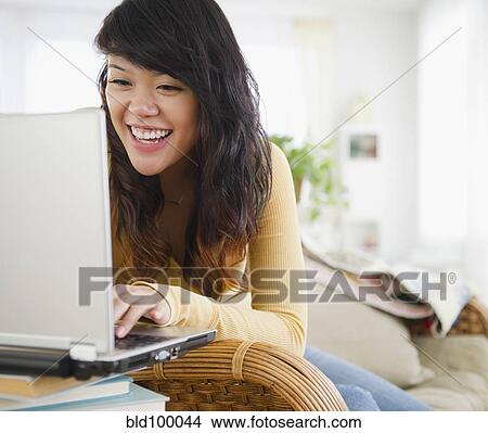 Picture - Pacific Islander woman typing on laptop. Fotosearch